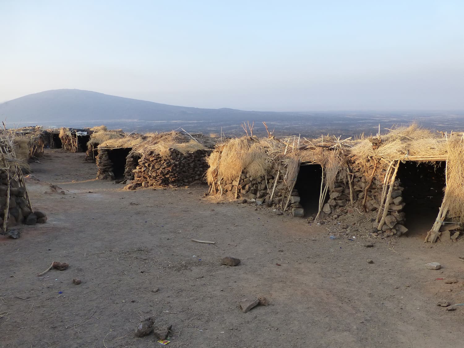 Low stone huts roofed with dry branches at the Erta Ale base camp