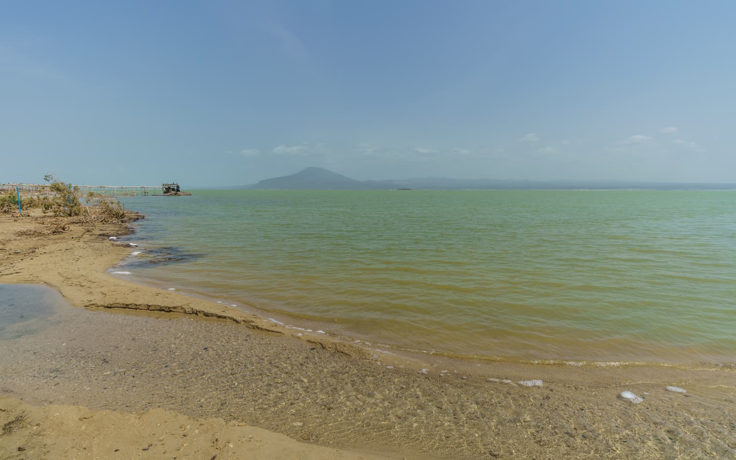 The calm turquoise waters of Lake Afrera with volcanic hills behind